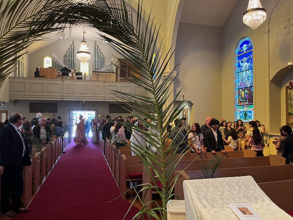 View down the center aisle during a church service, with parishioners in the pews.