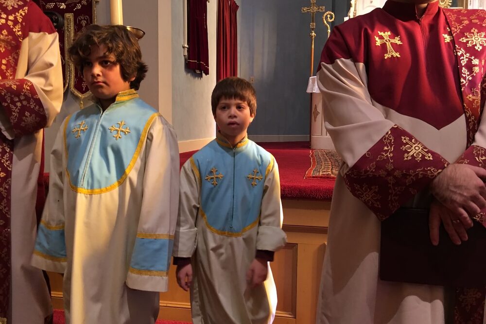 Two young altar servers standing in the sanctuary during a church service.
