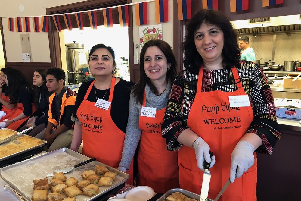 Volunteers serving food beneath Armenian flags in the church hall.