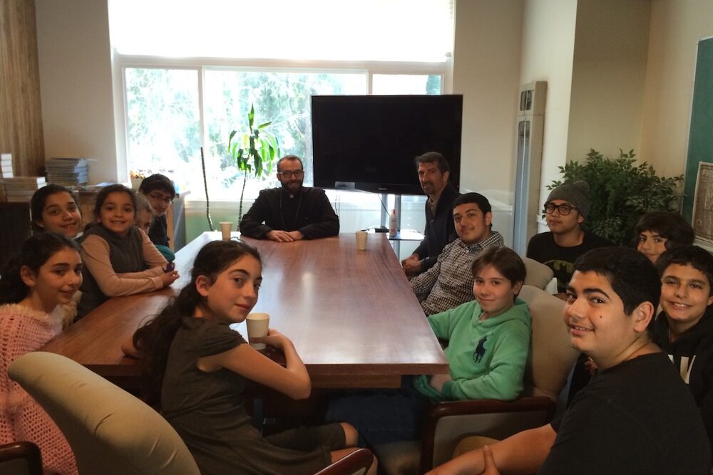 Young people gathered around a table in a church room.