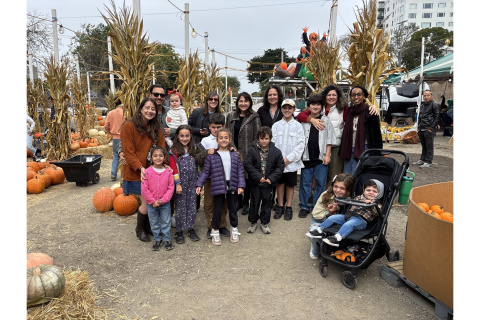 Children and adults pose together among pumpkins and tall cornstalks at Clancy’s Pumpkin Patch.